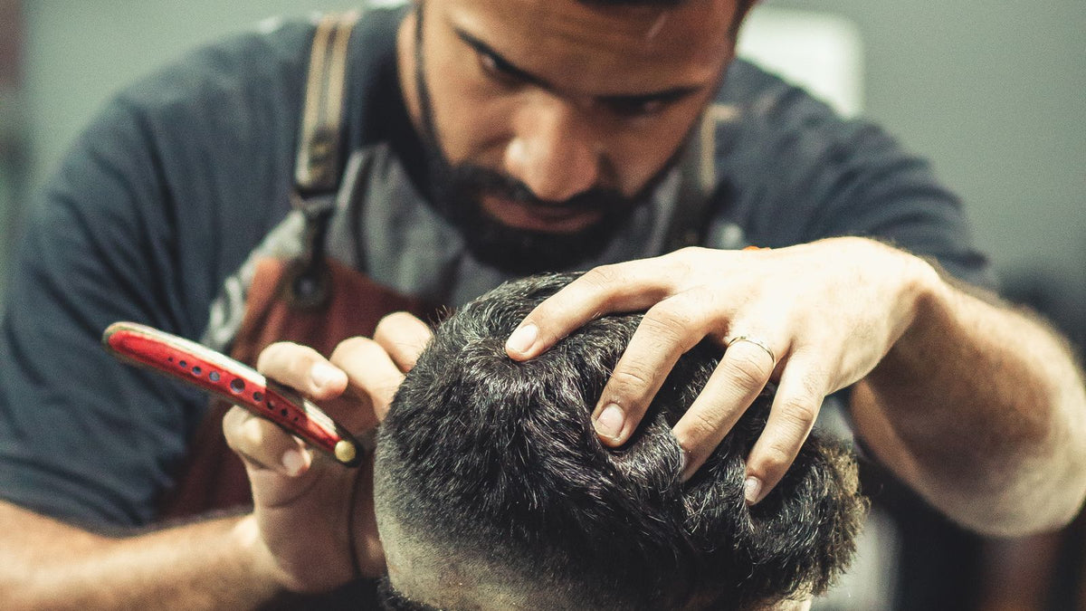 Frisør styler kort hår på mann i barbersalong